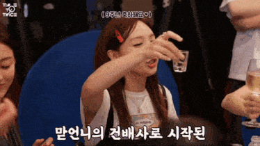 a woman holding a shot glass with a twice logo on the bottom