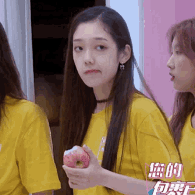 a girl in a yellow shirt is holding a donut in her hand