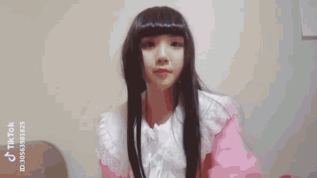 a girl with long black hair is wearing a pink dress and a wig .