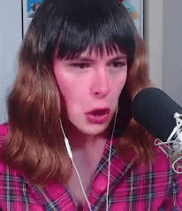 a woman wearing a plaid shirt is talking into a microphone .