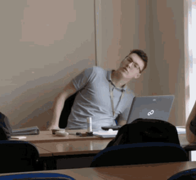 a man sitting at a desk with a laptop that says ' infinity ' on it