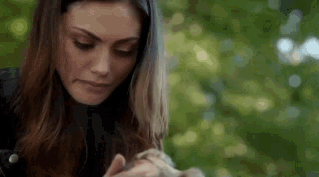 a close up of a woman holding a small animal in her hands .