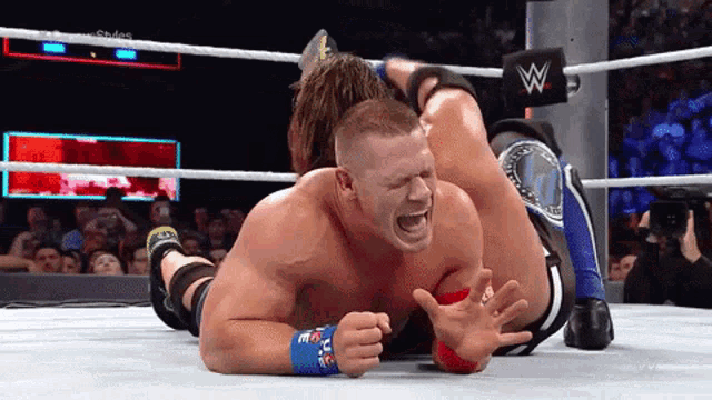 a wrestling match between john cena and aj styles with the letters w on the ring