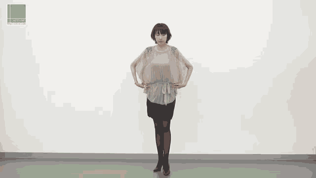 a woman stands in front of a white wall with a green sticker that says ' swatch '