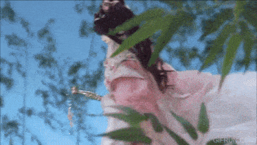 a woman in a pink dress is standing in a forest
