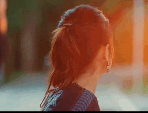 a woman wearing earrings and a ponytail looks to the side