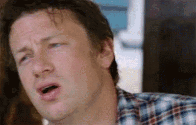 a man in a plaid shirt is making a funny face with his mouth wide open .