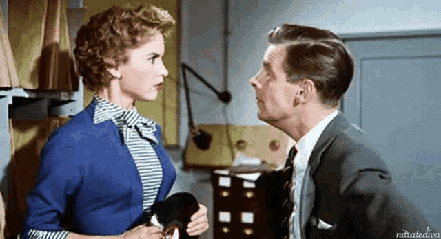 a man in a suit and tie is kissing a woman on the cheek in an office .