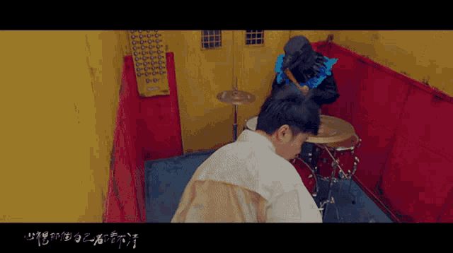 a man is playing drums in a room with chinese writing