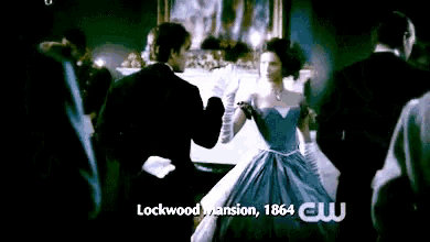 a woman in a blue dress is dancing with a man in a tuxedo in front of a sign that says lockwood mansion