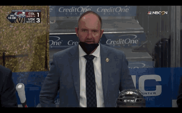 a man in a suit and tie stands in front of a credit one bank banner