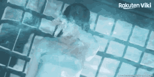 a man and woman are swimming in a pool with rakuten viki on the bottom