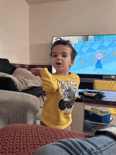 a little boy wearing a yellow monster truck sweatshirt