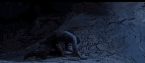 a person is laying on top of a mountain at sunset looking up at the sun .