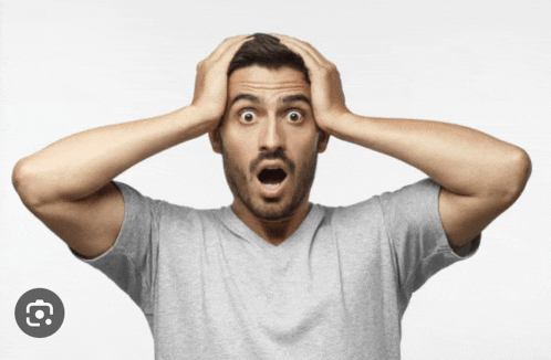 a man in a grey shirt is holding his head in his hands