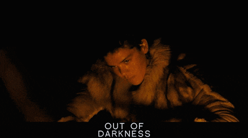a man in a fur coat with the words out of darkness written below him