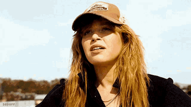a woman wearing a baseball cap and a black shirt is looking up .