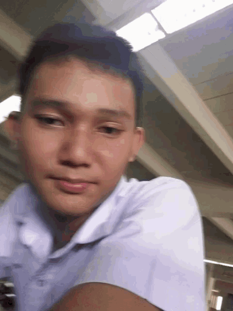 a young man in a white shirt is looking at the camera and smiling