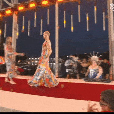 a man in a floral dress walks down the runway