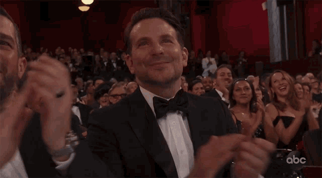 a man in a tuxedo applauds in front of an audience that says abc on the bottom