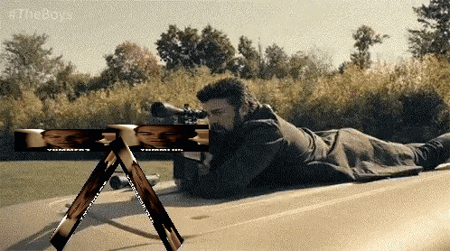 a man laying on the ground with a sniper rifle and a sign that says #theboy on it