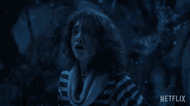 a woman in a striped shirt is standing in the dark with a netflix logo in the bottom right corner