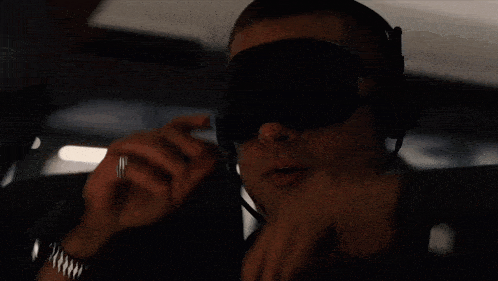 a man wearing a blindfold and a watch is talking on a cell phone