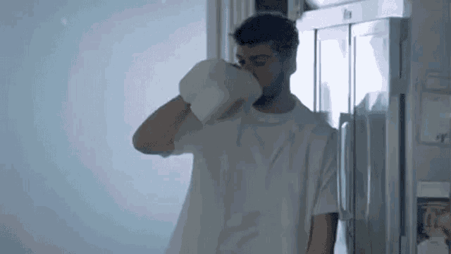 a man is drinking milk from a pitcher in a kitchen .