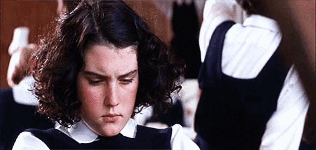 a girl with curly hair is wearing a black sweater and white shirt