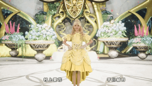 a woman in a yellow dress is standing in front of flowers with chinese writing