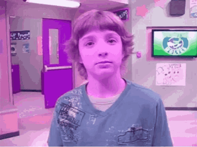 a boy in a blue shirt is standing in front of a sign that says ' u.s. army ' on it
