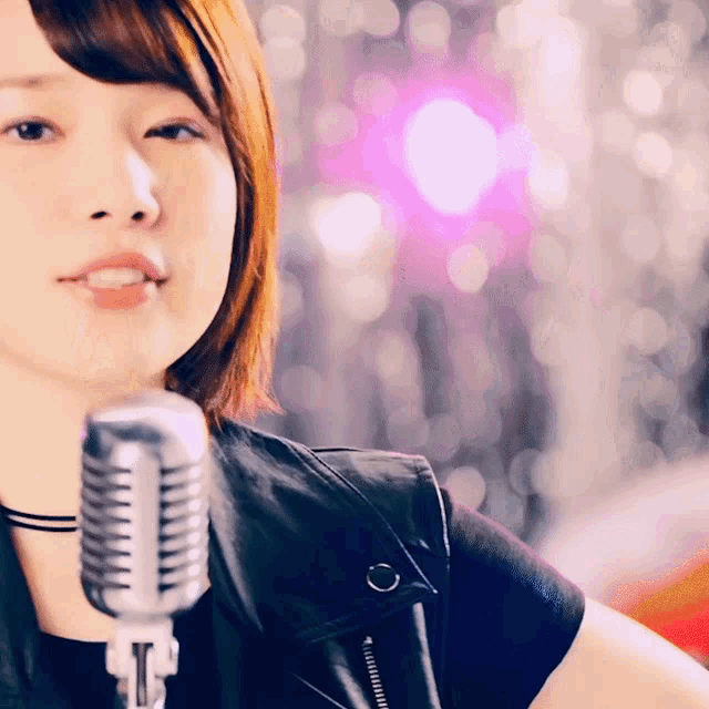a woman singing into a microphone with a purple background