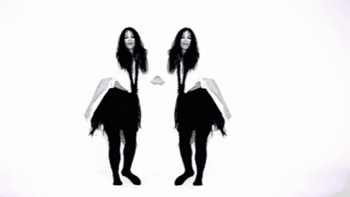 two women are dancing in front of a white wall