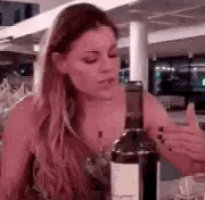 a woman is sitting at a table with a bottle of wine in her hand .