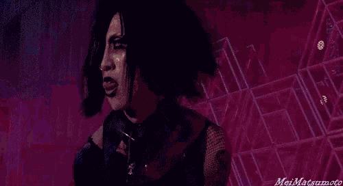 a man with dreadlocks is standing in front of a purple background .