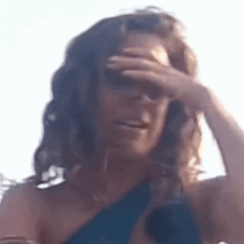 a woman wearing sunglasses covering her face with her hand