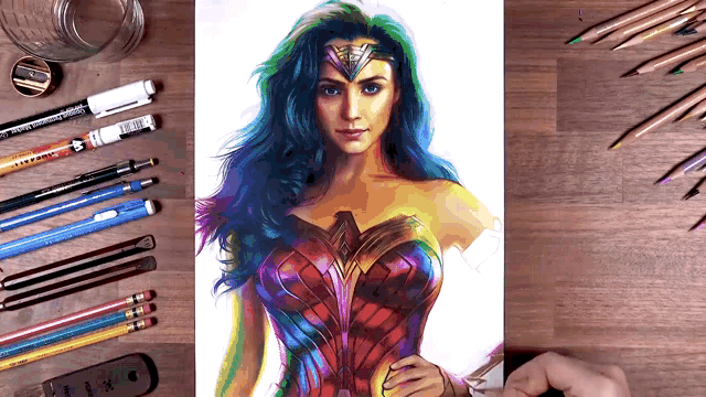 a drawing of wonder woman is surrounded by colored pencils and pens