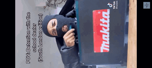 a man wearing a mask is holding a makita tool box