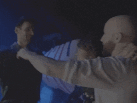 a man in a white shirt holds another man 's arm