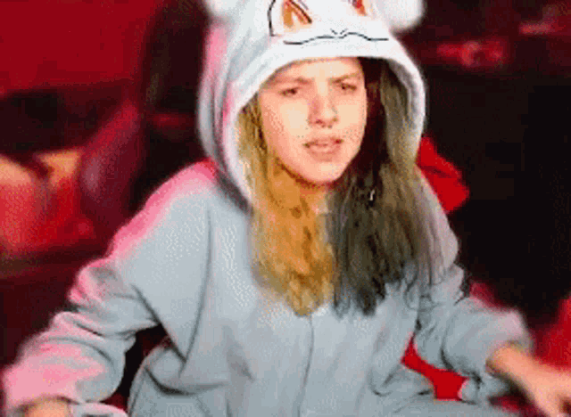 a woman wearing a cat hooded sweatshirt is sitting in a chair