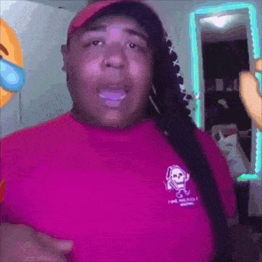 a woman is wearing a pink shirt with a skull on it and a hat .