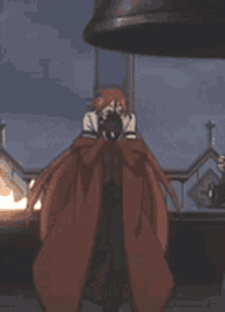 a man in a red coat is standing in front of a large bell