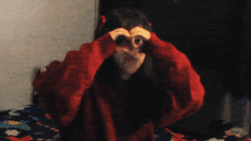 a girl in a red sweater making a heart with her hands