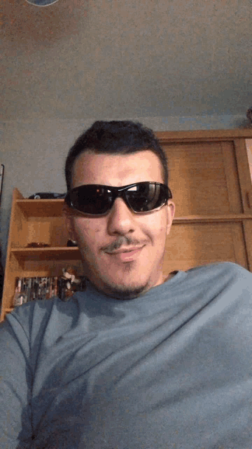 a man with a mustache wearing sunglasses and a blue shirt