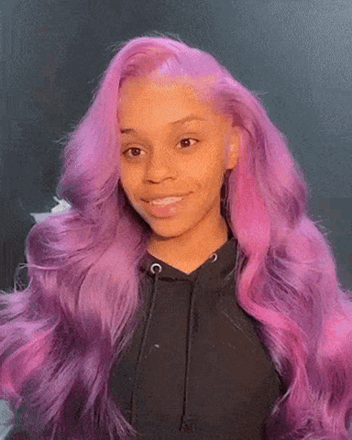 a woman with long purple hair is wearing a black hoodie .