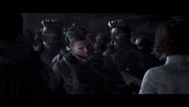 a man in a suit is standing in front of a group of soldiers and talking to a woman