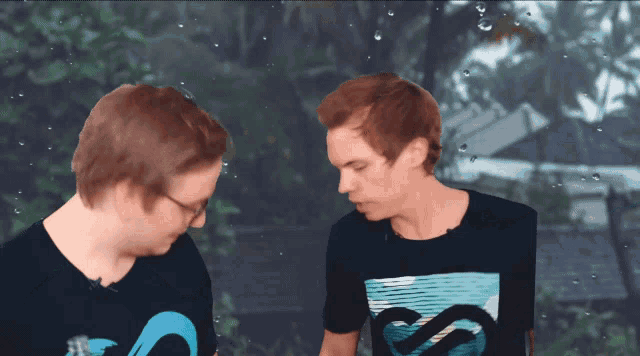 two men standing in front of a green screen with one wearing a shirt that says ss