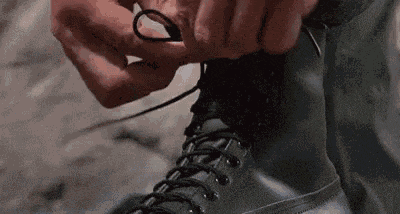 a close up of a person tying their shoelaces on a pair of black boots .