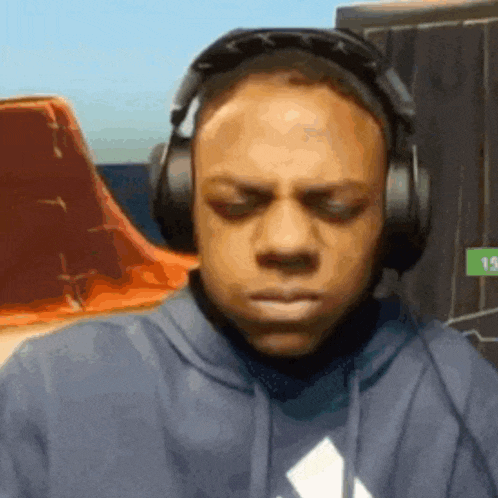 a man wearing headphones and a blue hoodie is making a face .