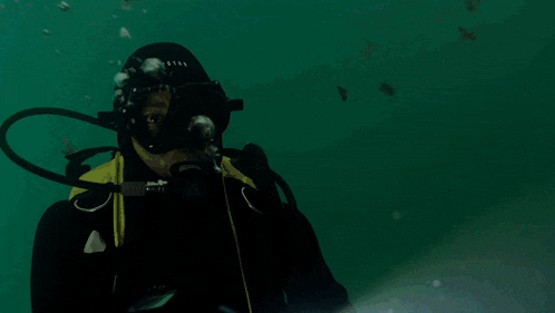 a scuba diver is holding a flashlight while swimming